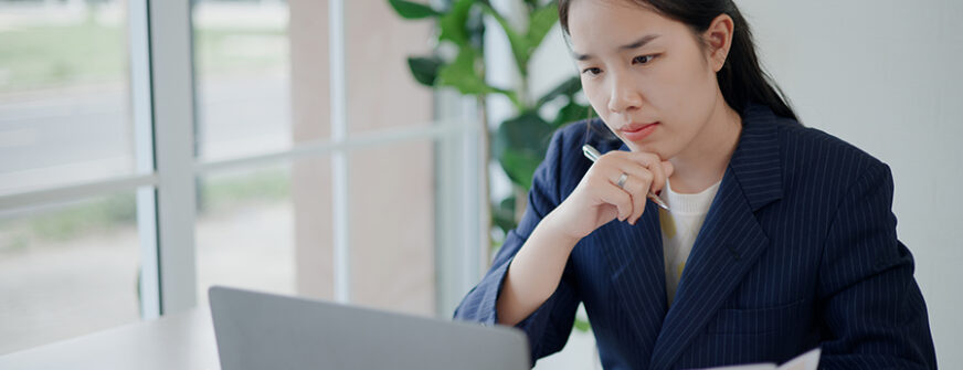 Portrait of Asian businesswoman in suit use laptop for work and analyze documents in small coffee shop. Work from anywhere, Remote working